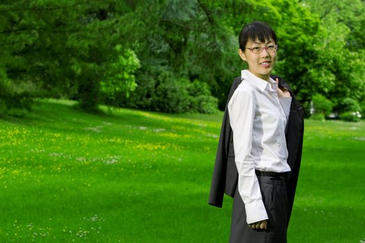 Environmentally friendly asian business woman outdoors in nature with green grass