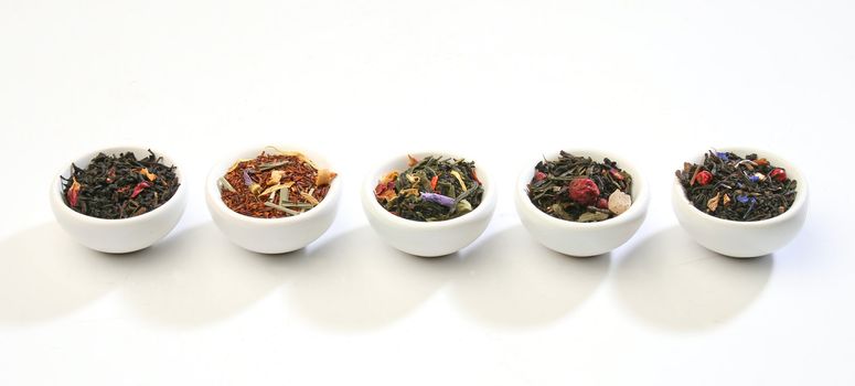 Various bowls of premiun tea leaves blends, over white background