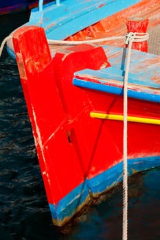 Stern and rudder of small old greek fishing boat moored in harbor.