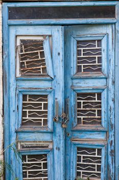 Peeling blue paint on exterior entrance door of abandoned building, in desperate need of major renovation job.