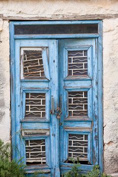 Peeling blue paint on exterior entrance door of abandoned building, in desperate need of major renovation job.