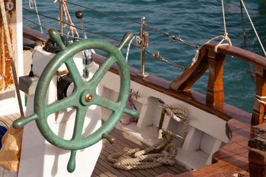 Green steering wheel of small old greek fishing boat moored in harbor.