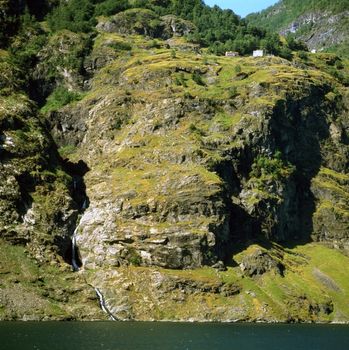 Hills around fjord with house