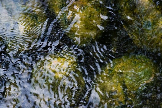 Boulders under and ripples in surface of water 