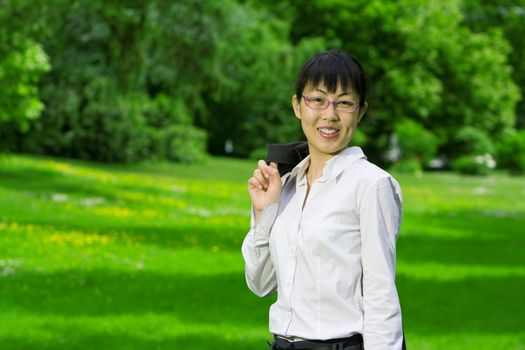 Environmentally friendly asian business woman outdoors in nature with green grass