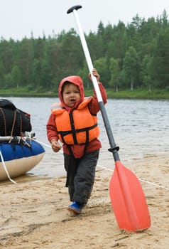 Little boy in a life jacket handing an oar