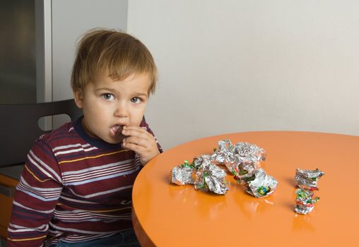 Little boy sitting at a table eating chocolates