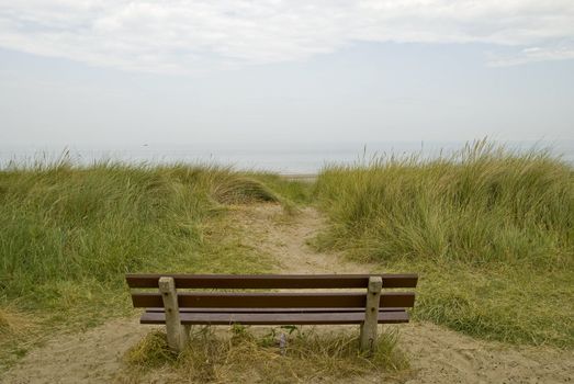 An empty bench in the dunes looking out to sea, in the Netherlands