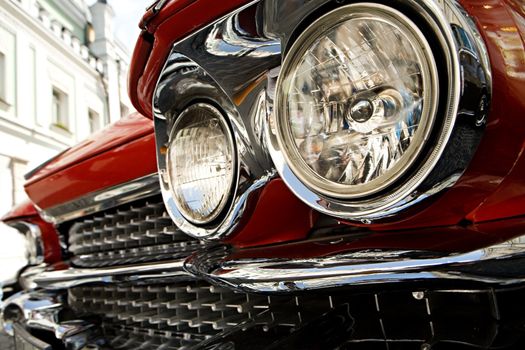 Forward headlights and lattice of the ancient red car close up
