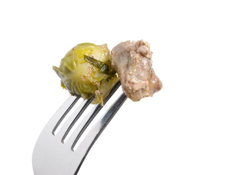 Meat and brussels sprouts on fork.a white background