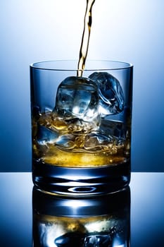 Filling of a glass of whisky with ice
