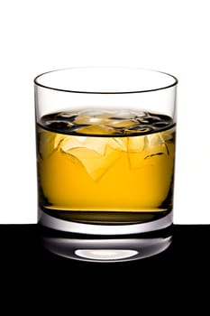 The shined glass of whisky with ice stands on a black table
