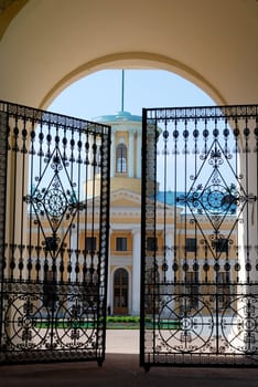 Half-open wrought iron gates with classical style building as background. Entrance to courtyard of Archangelskoye estate, Moscow, Russia