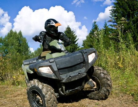 Sportsman riding quad bike at the summer forest
