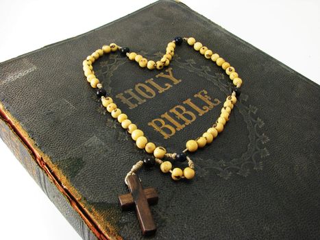 A rosary laying on a worn antique Bible.