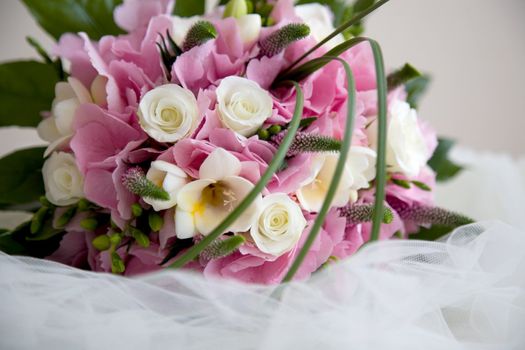 Lovely pink and white wedding bouquet lying on top of the veil
