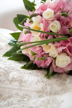 Beautiful wedding bouquet lying on top of the wedding dress