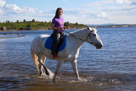The girl led the horse to swim. Summer landscape.