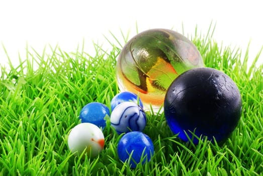 Marbles on grass, isolated on a white background.