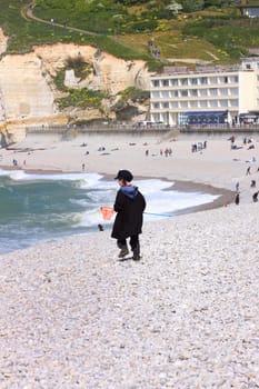 a young child dressed as a fisherman plays on the beach