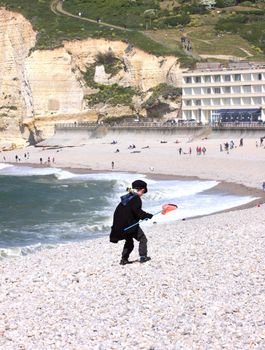 a young child dressed as a fisherman plays on the beach