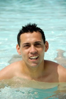 A young latin man is swimming in pool