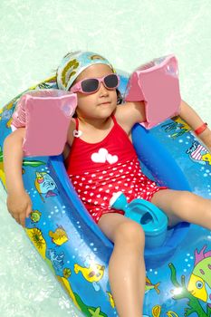 Young child is relaxing in boat in swimming pool.