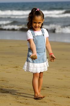 Child is playing with sand on beach.
