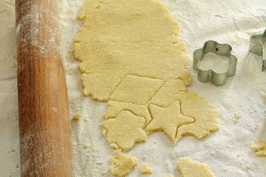 shaped cut dough near rolling pin and cutter on the table, shallow DOF