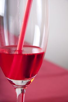 Red cocktail in a glass with a straw