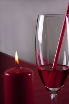 Red cocktail in a glass with a straw and a bottle