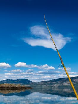 Fishing rod bends under weight of fish that just took lure in Lake Laberge, Yukon Territory, Canada