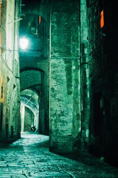 Ghostly illuminated narrow street in old city of Siena at night, Tuscany, Italy, Europe