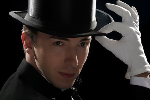 young magician with high hat on black background