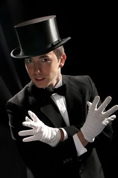young magician with high hat on black background