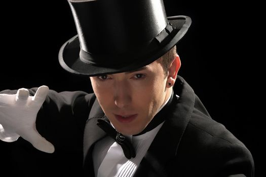 young magician with high hat on black background