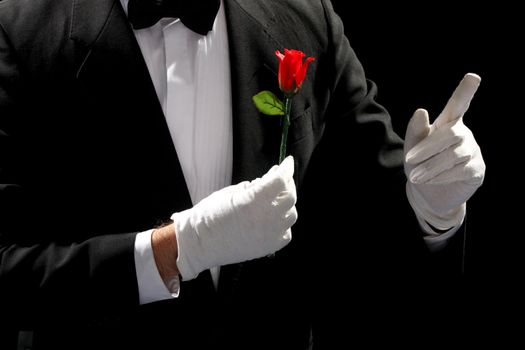young magician performing red rose on black background