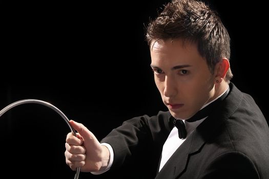 young magician with silver metal rings on black background 