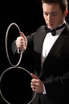 young magician with silver metal rings on black background 