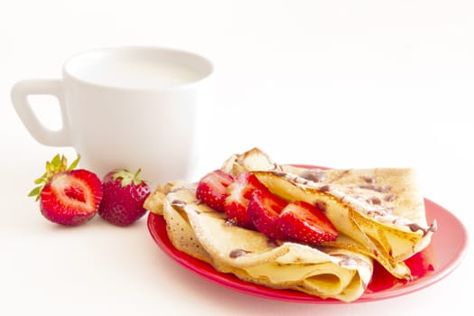 sweet pancakes with strawberry and cup of milk on white background