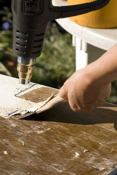 portrait of renovation; removing old paint using scraper and heat gun