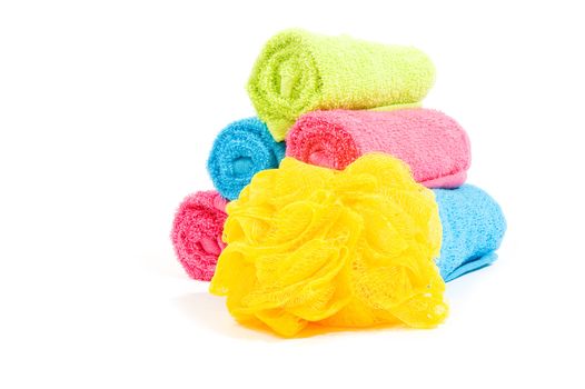 Colorful towel rolls with yellow bath sponge on a white background 