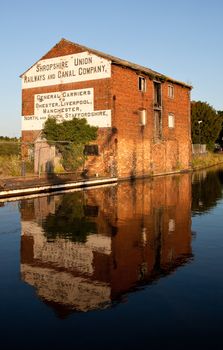 Old warehouse reflected on still evening in the waters of the canal