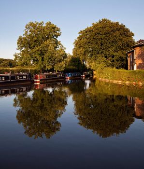 Calm view of the canal near Ellesmere with the barges reflected in the water