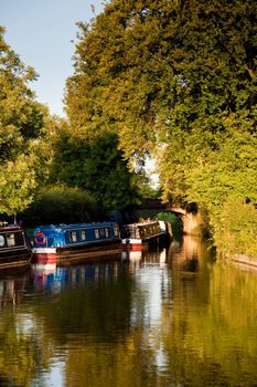 Vertical format of canal barges on river reflected in the calm water