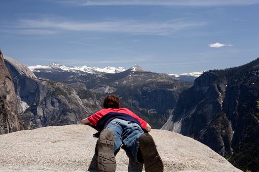 Male hiker at viewpoint at top of Yosemite falls overlooking distant mountains