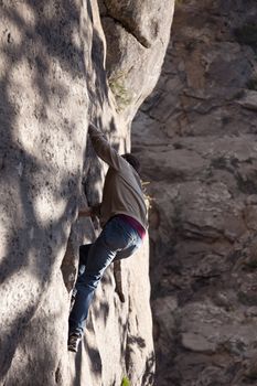 Close up of young male hiker climbing rocks besides a waterfall