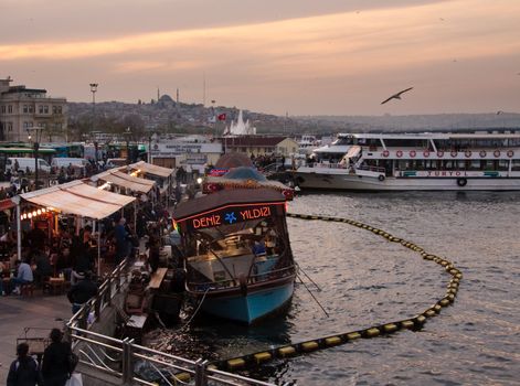 Food ships bobbing in Bosphorus by Galata bridge in Istanbul in the evening