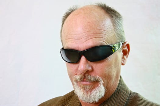 Man with sunglasses and slight smirk on his face.