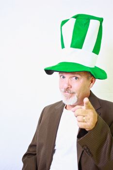 Middle aged man with tall green and white top hat pointing finger at camera.